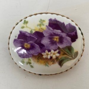 Z125- Vintage brooch that has a gold colored edge with a floral print.